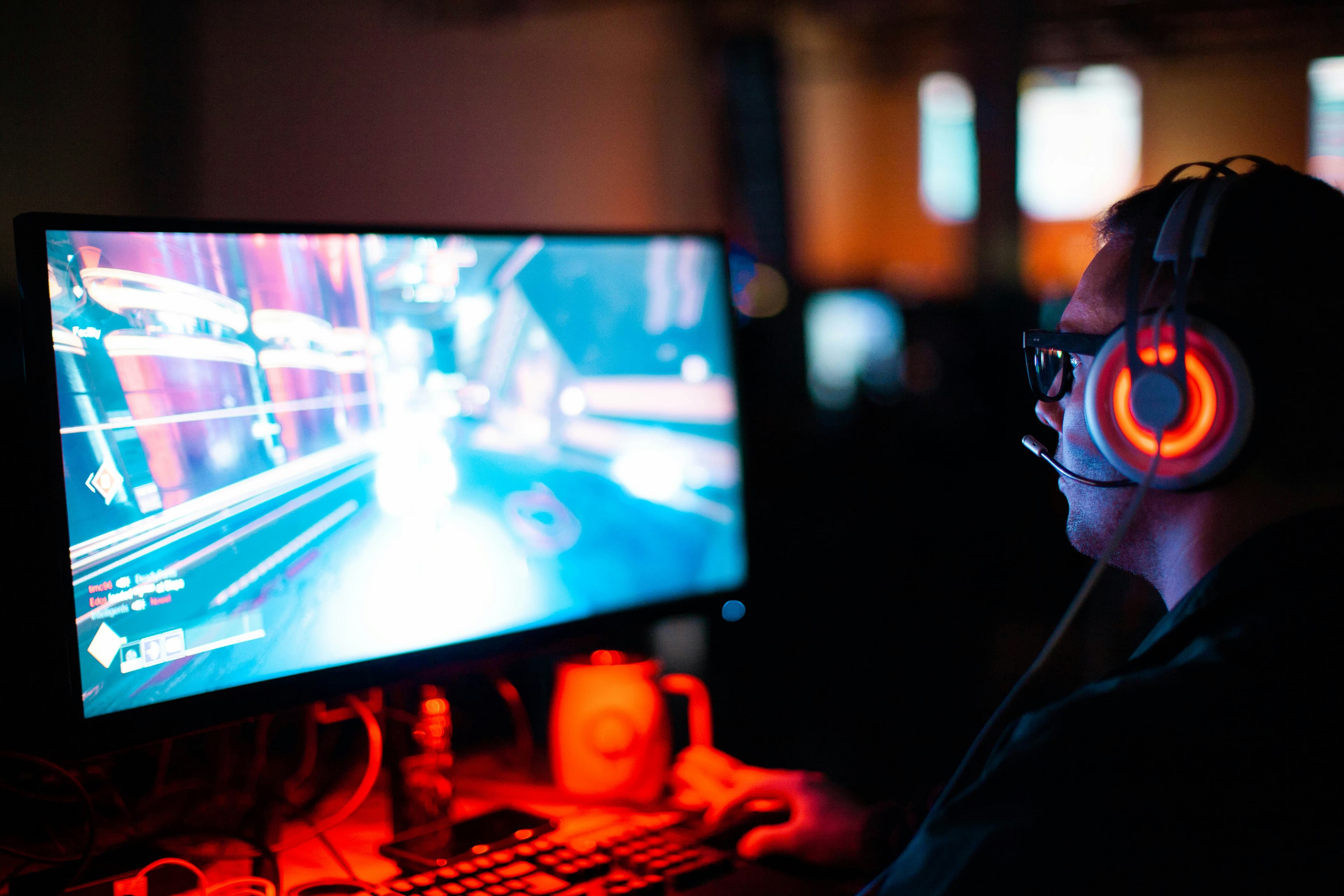 Геймер играет в шутер от первого лица за компьютером с RGB-подсветкой