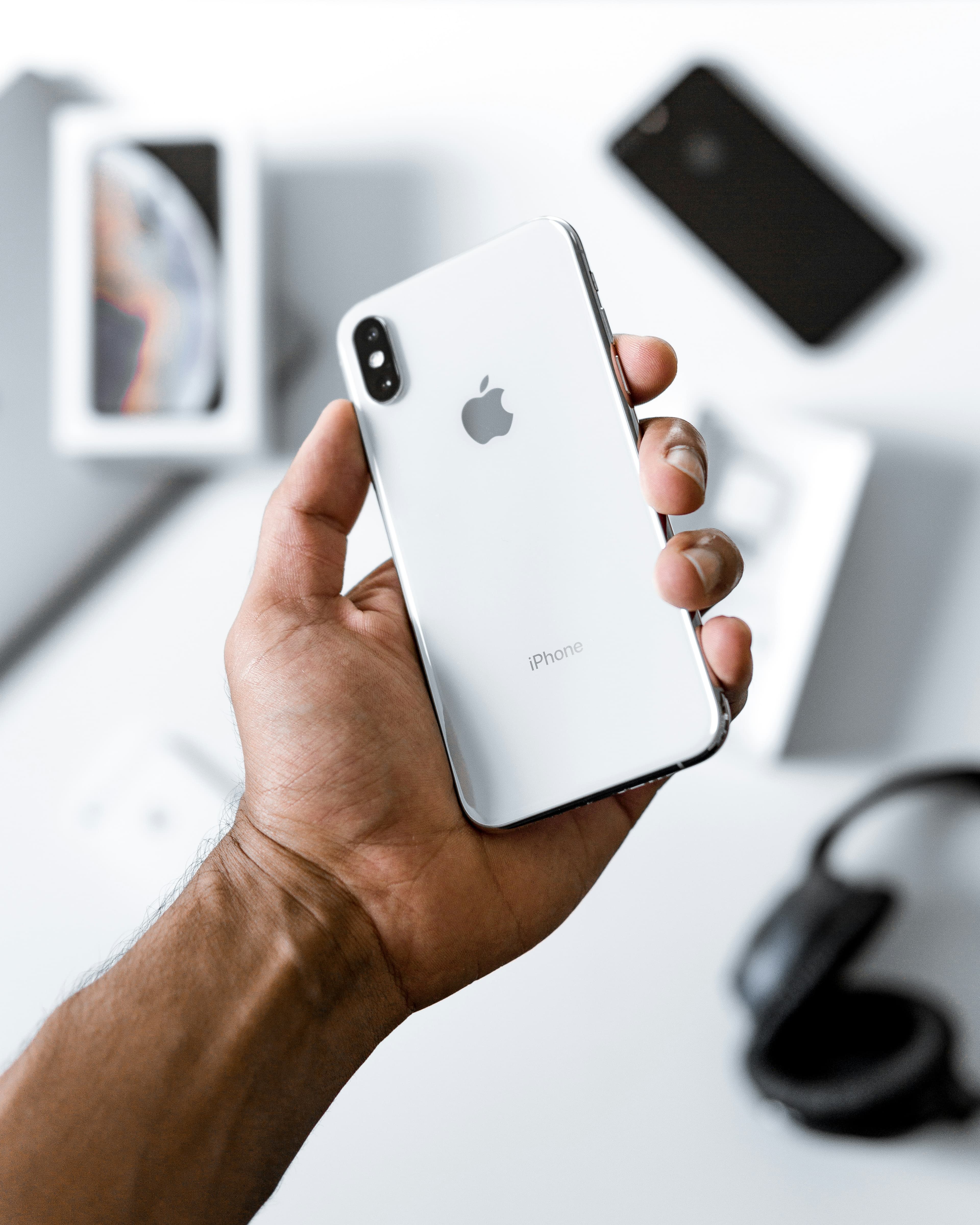 Человек держит в руке iPhone с включённым экраном