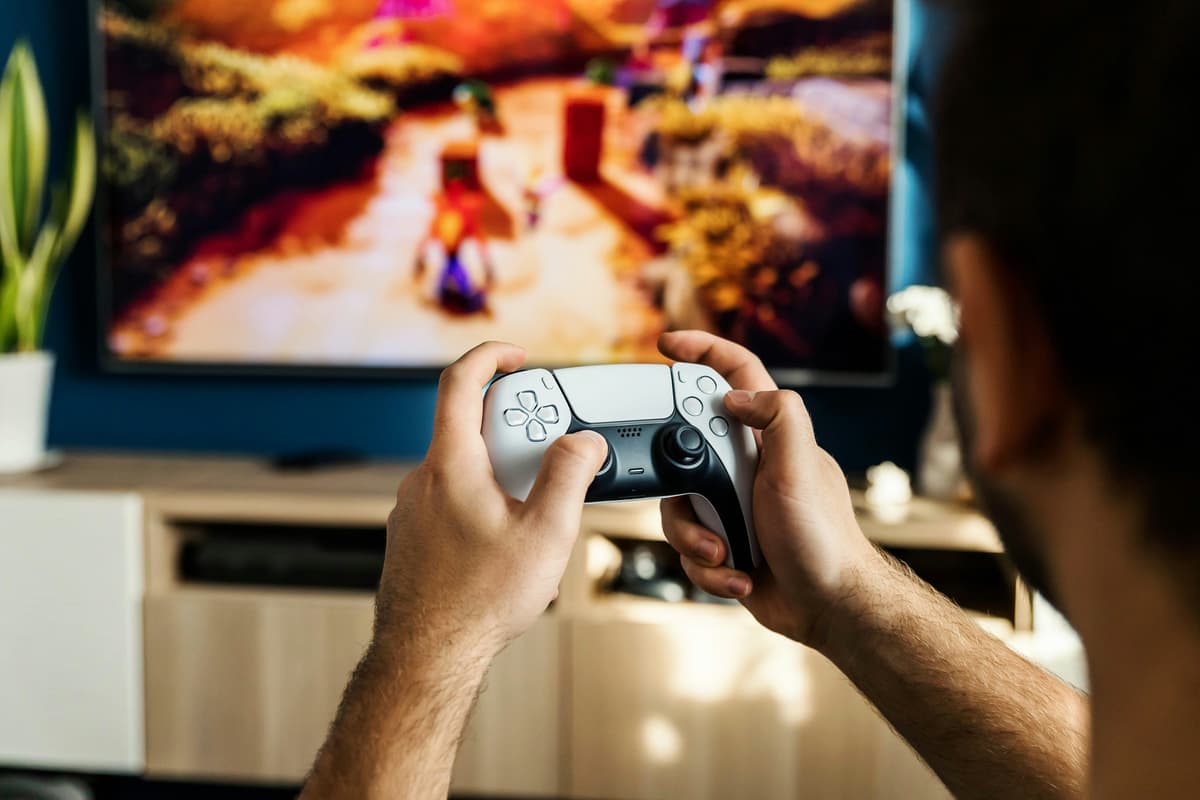Мужчина играет в видеоигру с контроллером перед экраном