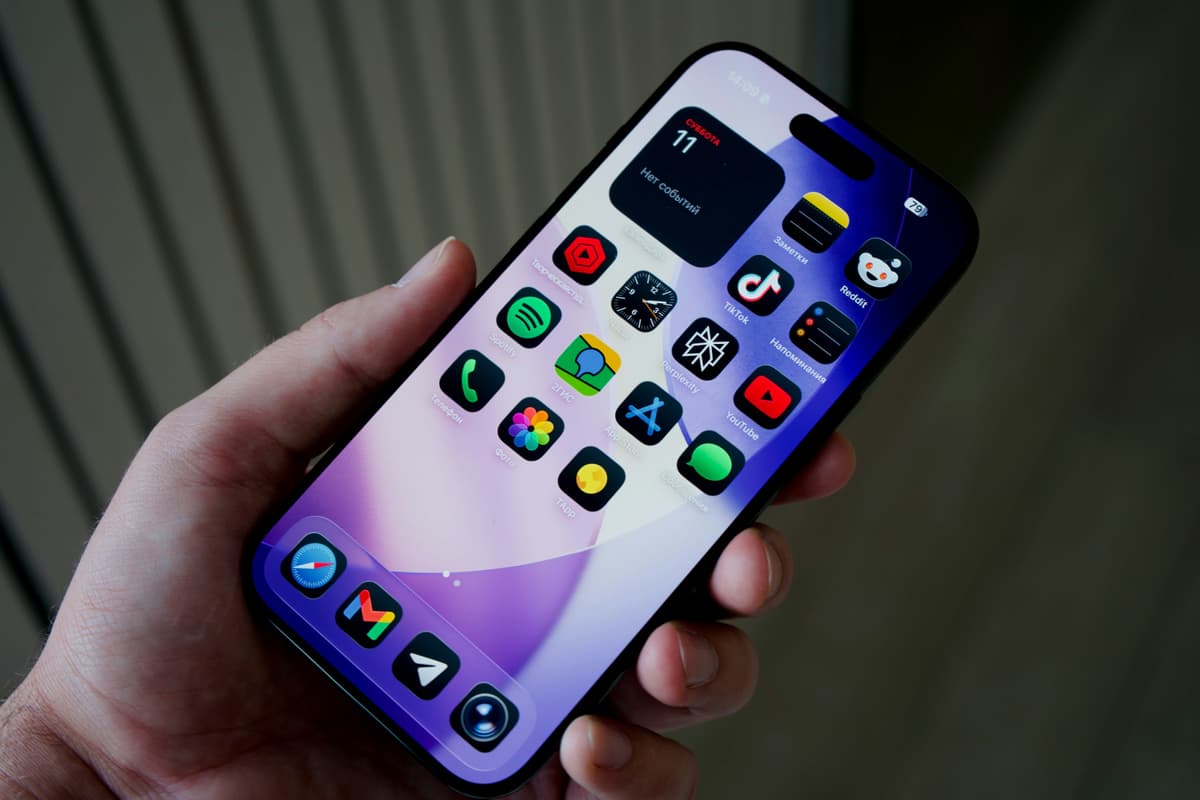 Рука держит смартфон с разноцветными иконками приложений
